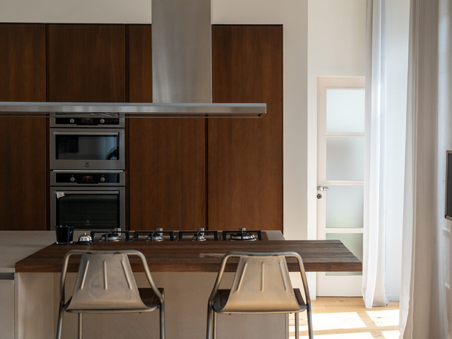 Cucina con colonne in legno scuro, isola centrale e sgabelli in metallo