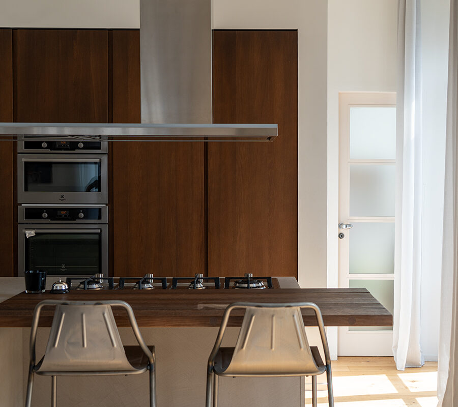 Cucina con colonne in legno scuro, isola centrale e sgabelli in metallo