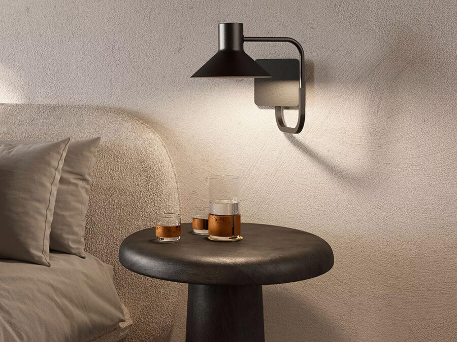 Lampada da parete Zava sopra un tavolino scuro accanto a un divano bouclé