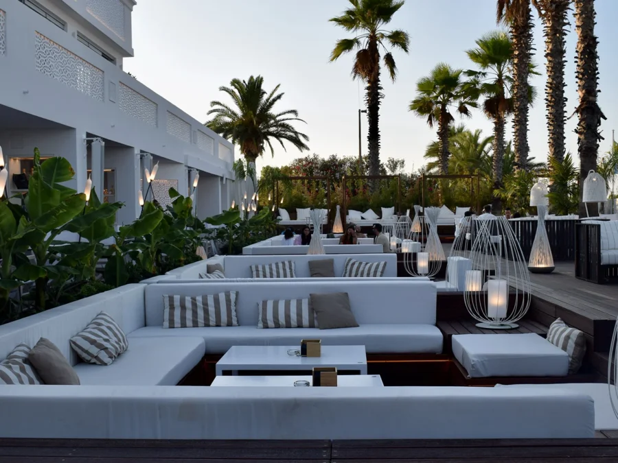 Lounge all'aperto con divani bianchi, palme e piante mediterranee