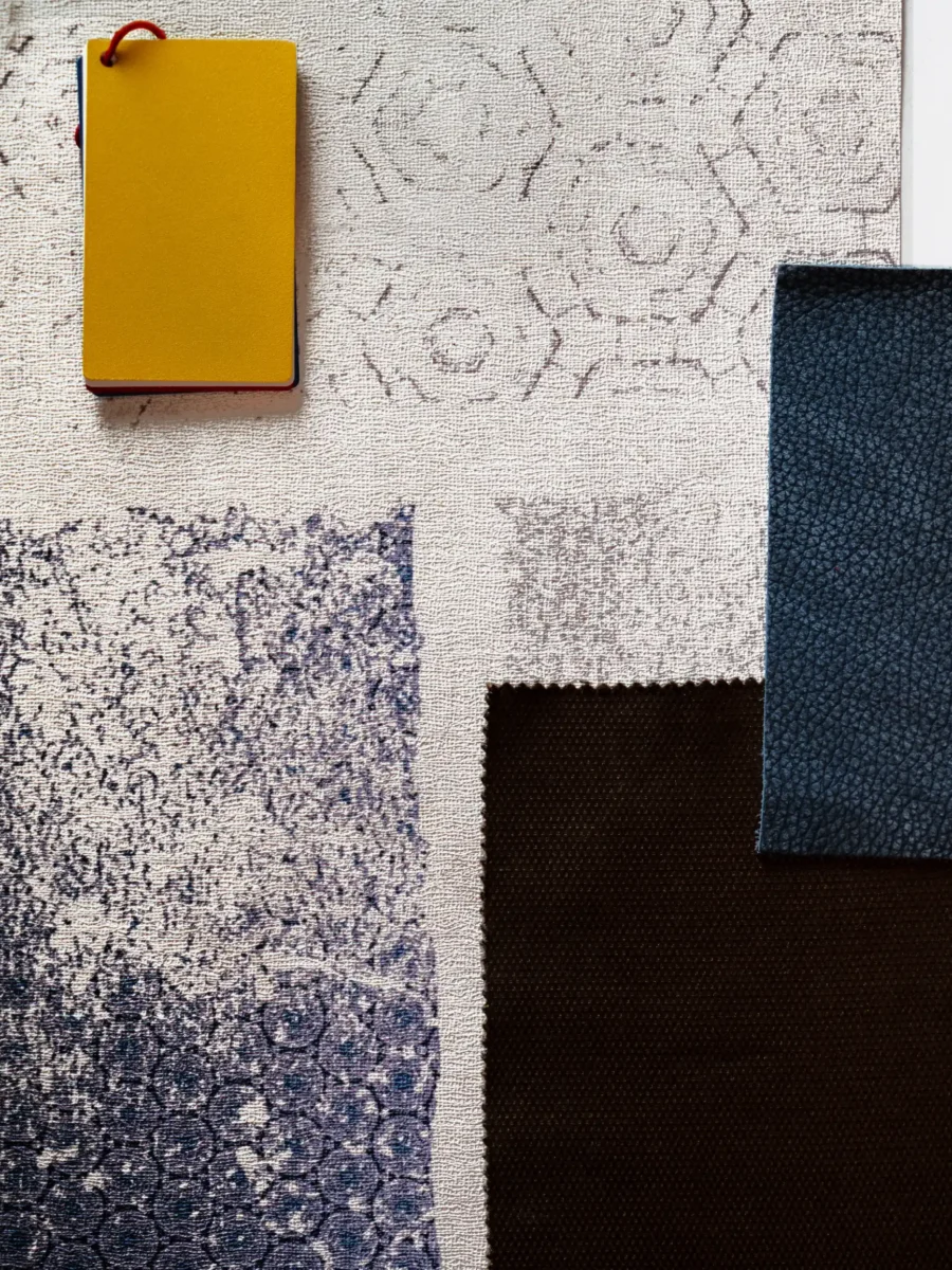 Moodboard con campioni di tessuti in blu, avorio e marrone e una cartella gialla