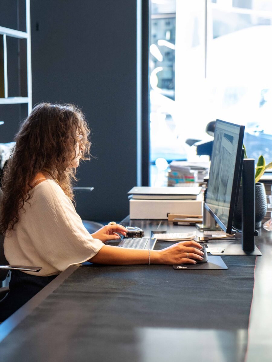 Progettista al lavoro alla scrivania nello studio, davanti a due monitor