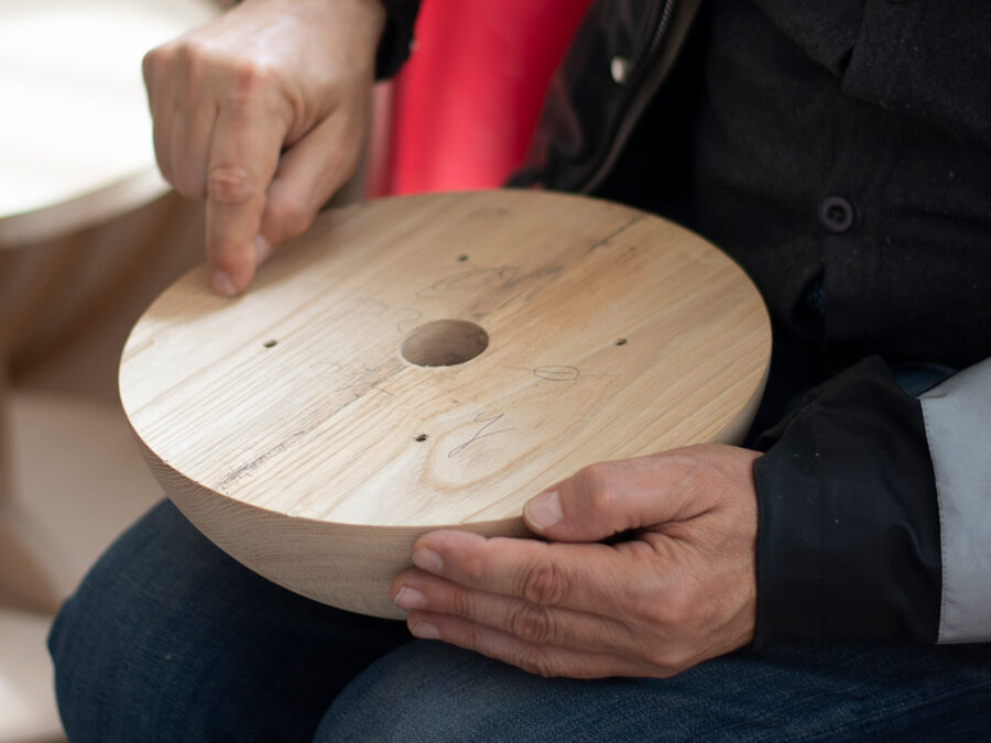 Artigiano che tiene in mano un elemento in legno tornito appena lavorato