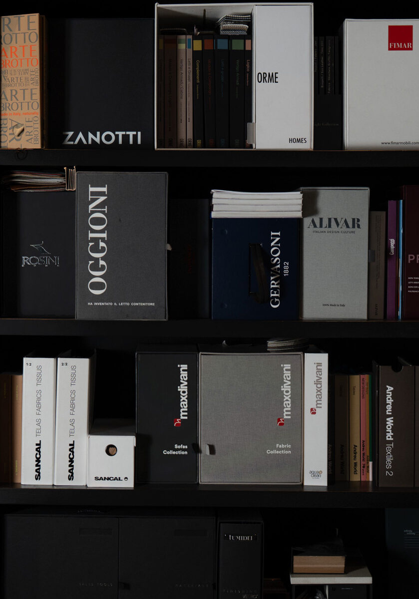 Libreria nera con cataloghi di aziende di arredo come Zanotti, Oggioni e Alivar